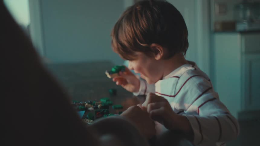 Boy plays with lego toys while adult watches