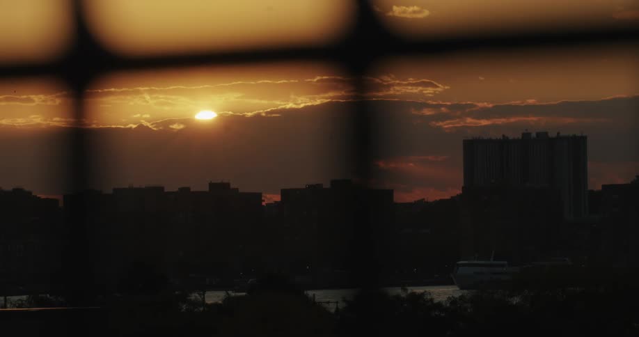Sunset over a city seen through a fence