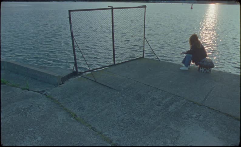 A woman is sitting by the water