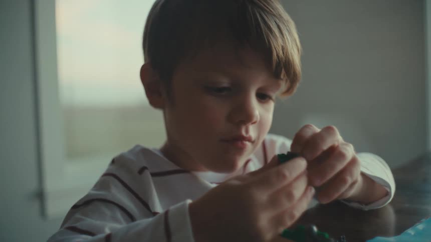 Young boy playing with moving a small toy around in his fingers and expressing surprise about the movements