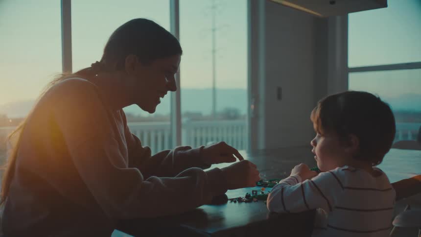 A mother and son play with legos together