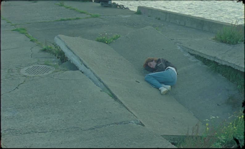 Young woman lays over a broken concrete slab caught on vintage film