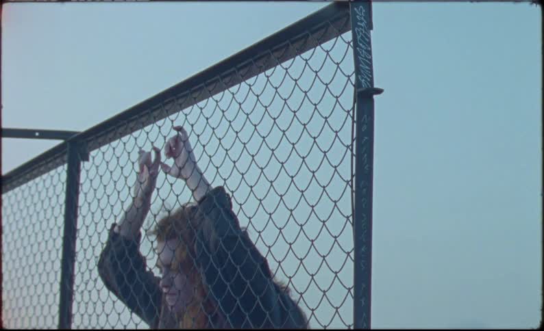 A teenager is leaning against the fence