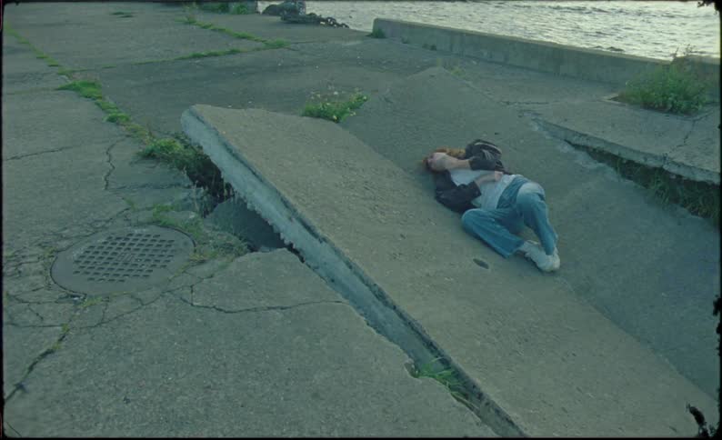 A person lying on the ground near the sea coast