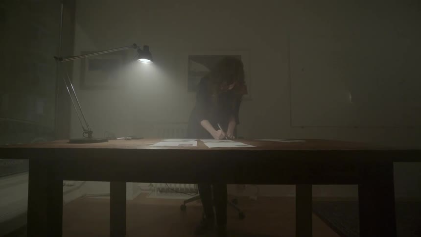 A hardworking professional reviews important documents while working late in a quiet moody office.