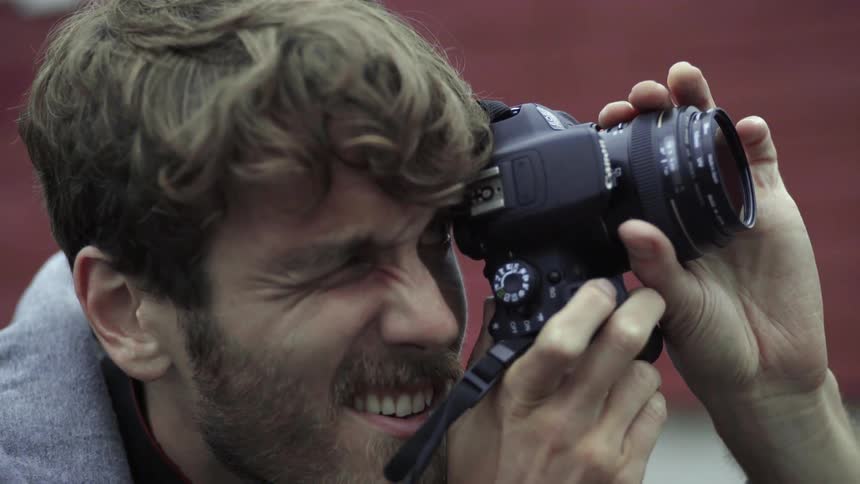 A meticulous creative photographer adjusts his camera settings to catch the perfect light.