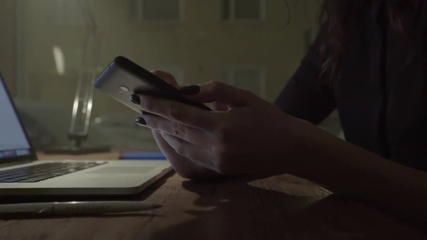 A woman uses her mobile phone to coordinate project details during a work session.