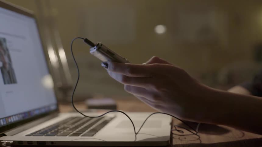 A multitasking professional checks her mobile notifications while working on a computer at night.