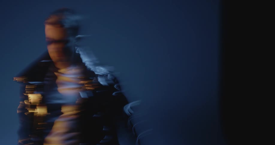 Male model wearing fashionable jacket stands in front of photo backdrop during photo shoot