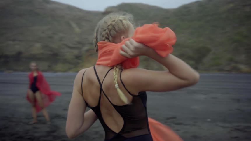 Elegant artists synchronize their movements with the fierce wind on a desolate beach.
