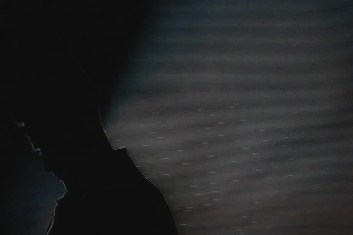 Silhouette of a man in front of a spotlight with vhs video distortion