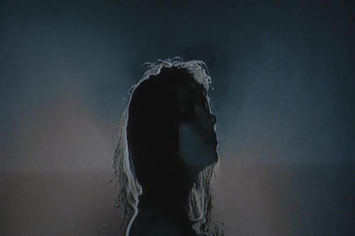 Silhouette of a woman in front of a spotlight on vhs video distortion