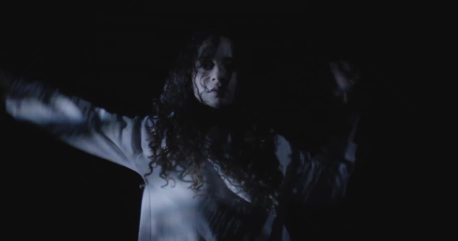 Close up of a woman dancing inside a dimly lit room