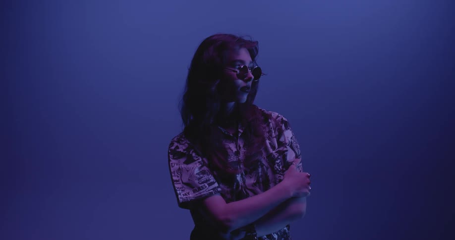 A female modeling sunglasses and a printed shirt on a blue background