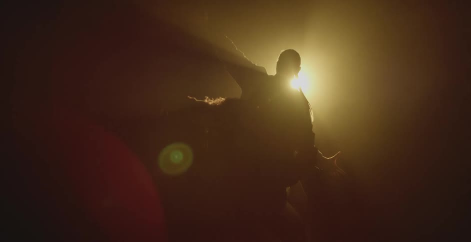 Silhouette of a couple dancing in front of a spotlight