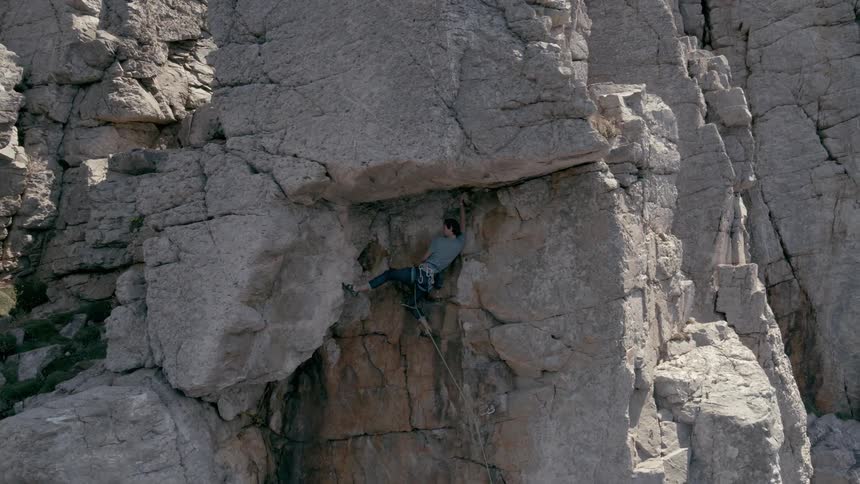 Aerial view of a man climbing a rock wall in the cliffs