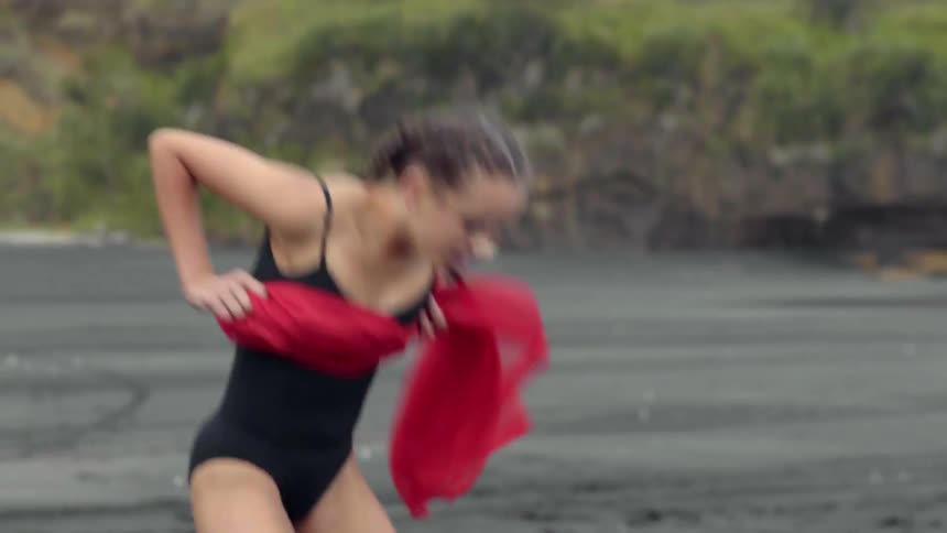 An elegant performer expresses intense emotional storytelling through movement on a moody beach.