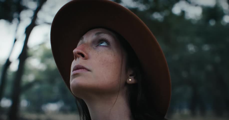 Young woman with a hat looks up in a park
