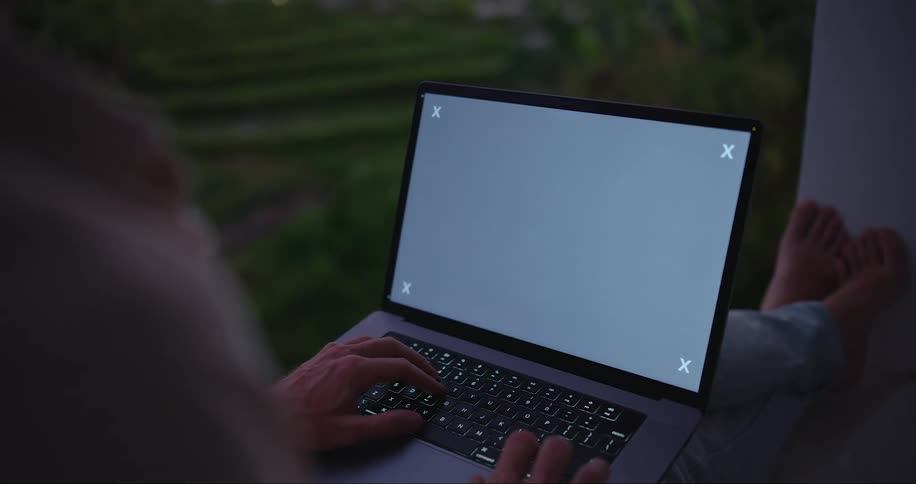 A person typing on a laptop with a gray screen
