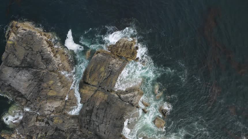Waves crash on the rocks below