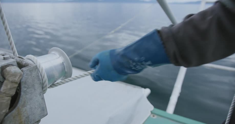 A fisherman pulls rope on the boat