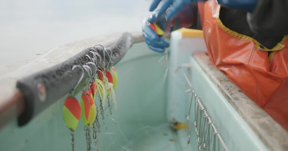 A fisherman is hanging hooks on the boat