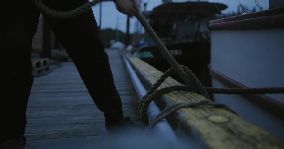 A man ties his boat to the dock with rope