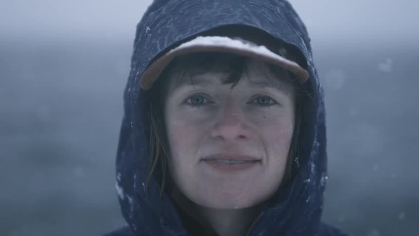 Woman looking at the camera smiles during a light snow storm