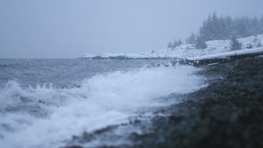 The waves crash against the snowy shore