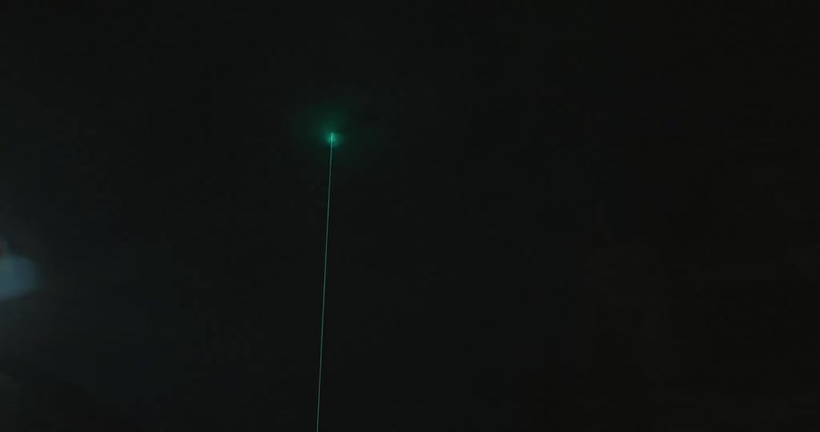 Green laser from a tower shining on the city at night