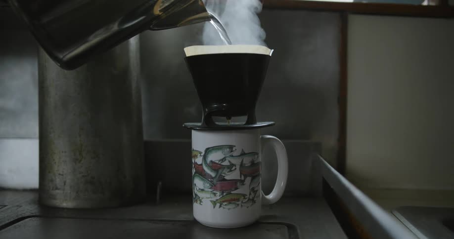 Hot water pours from kettle through pour over filter to make a single mug of coffee