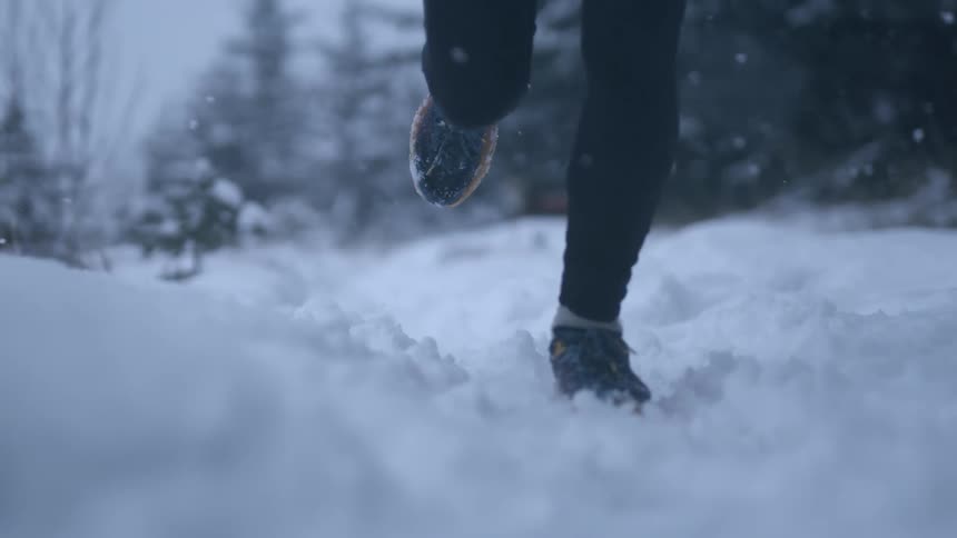 Woman jogging in the snow, close up of feet