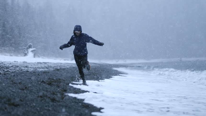 Woman running on the beach under a heavy snowstorm