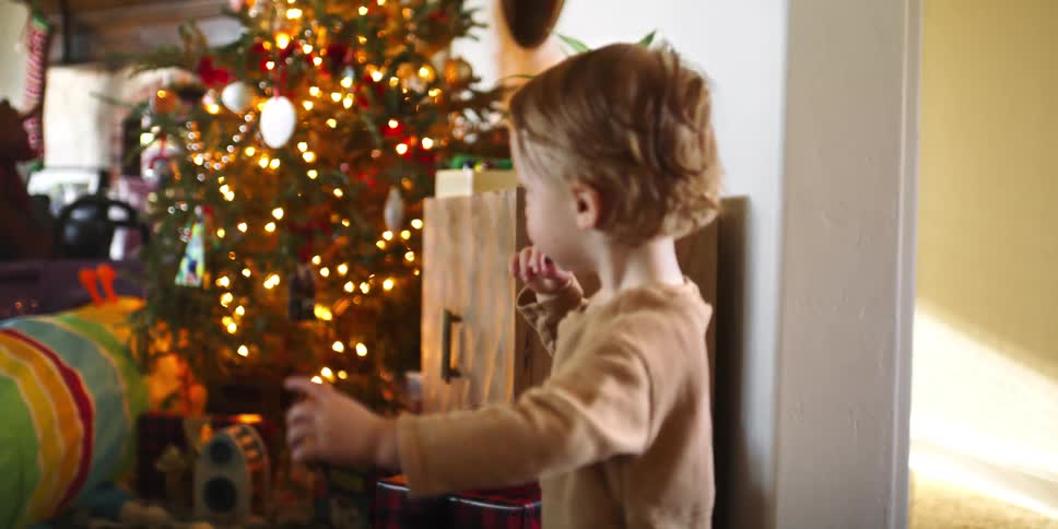 Toddler finds toys under the christmas tree