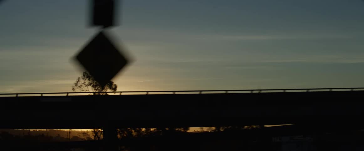 Sun glares from red tinted horizon casting bridge into silhouette