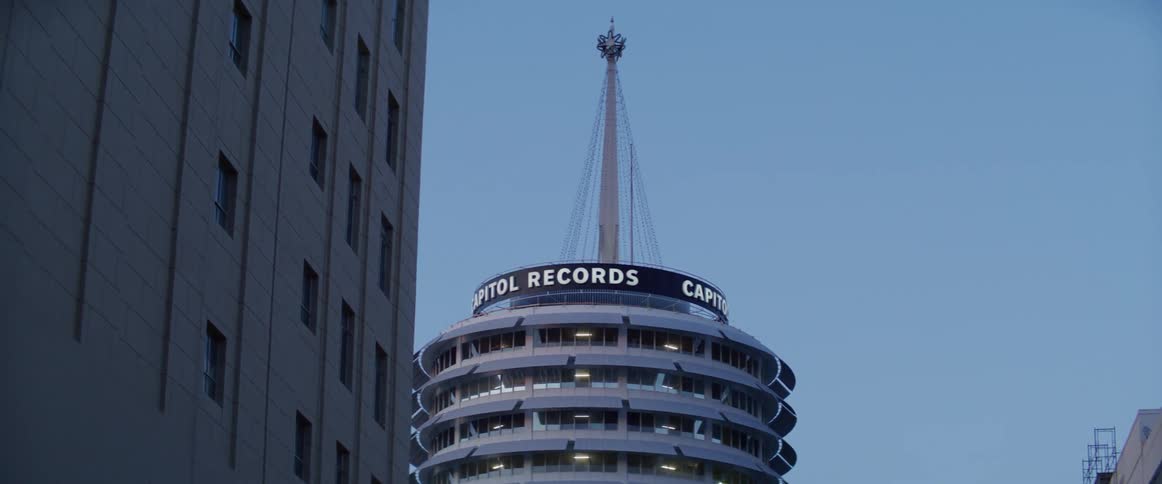 Cylindrical building tower capital records at dusk from street level perspective