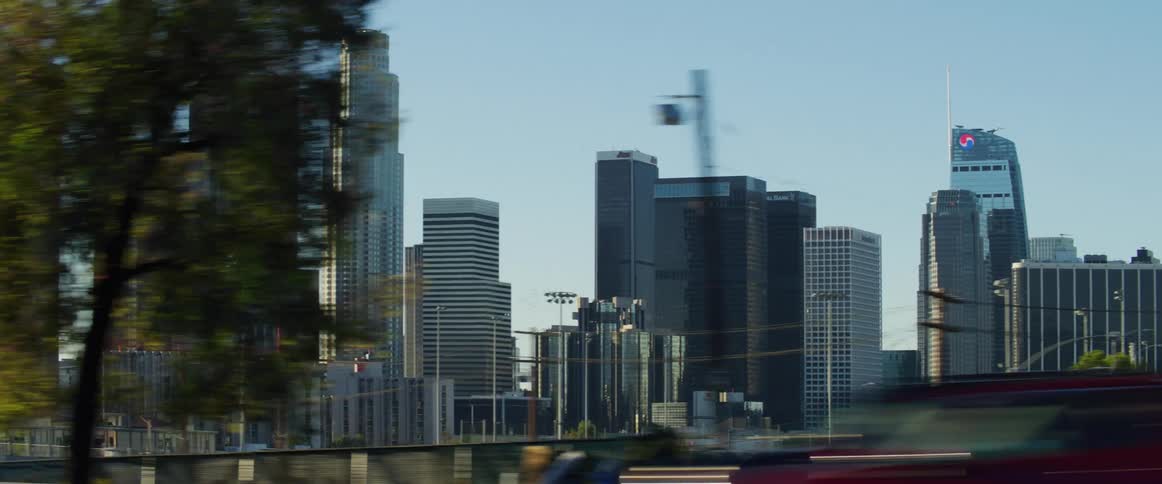 Vehicles drive along highway past city skyline