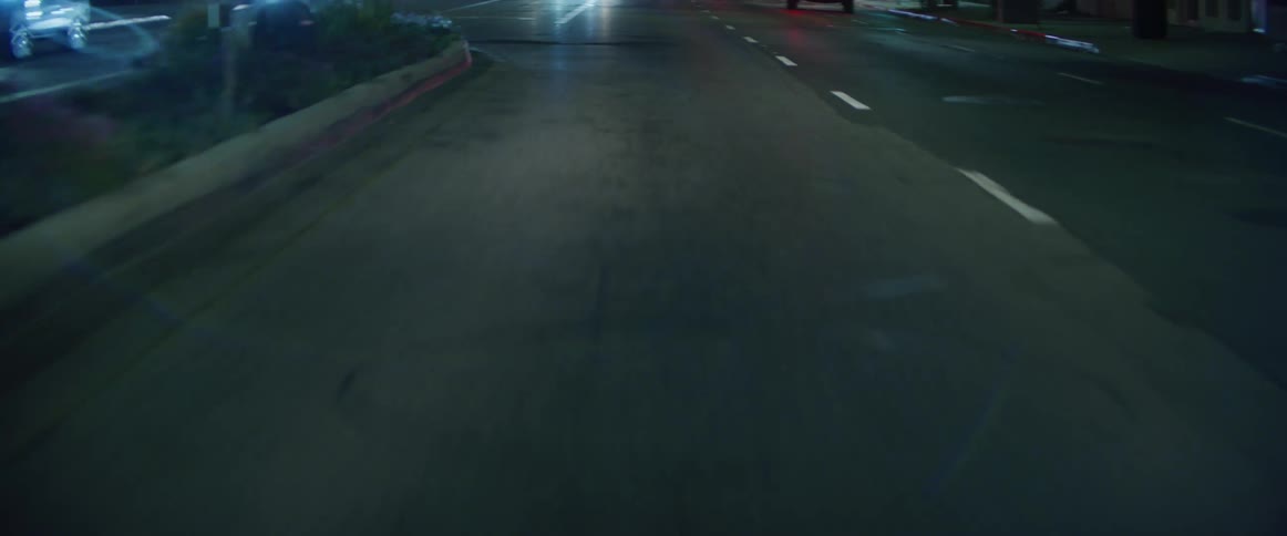 City street at night approaching an intersection with reflective car lights