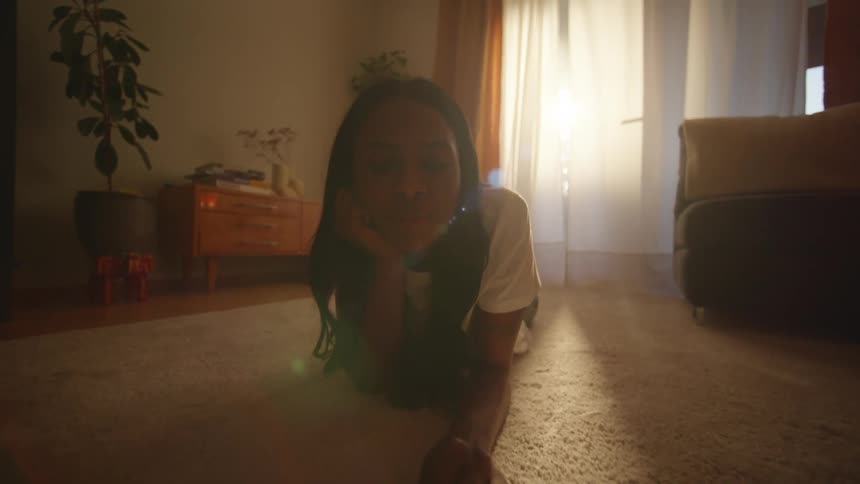 A woman is reading a book on her living room floor