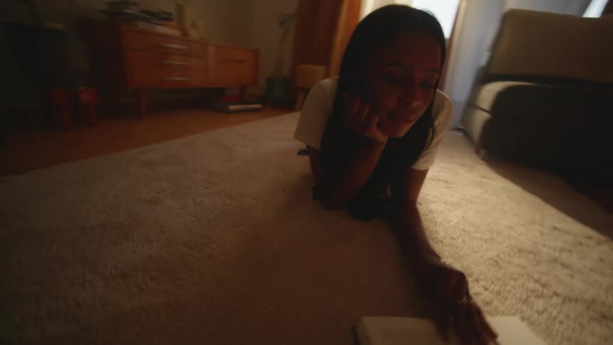 Young woman reading a book on the livingroom floor
