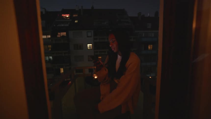 Woman sitting on a small balcony text on her phone