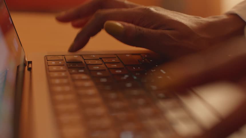 A hand typing on a laptop on a table