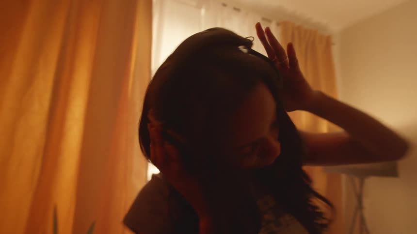 Young woman listening to music dances in her room