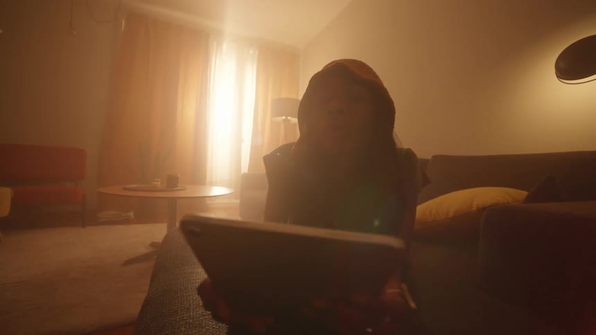 A woman using a tablet lying on the couch