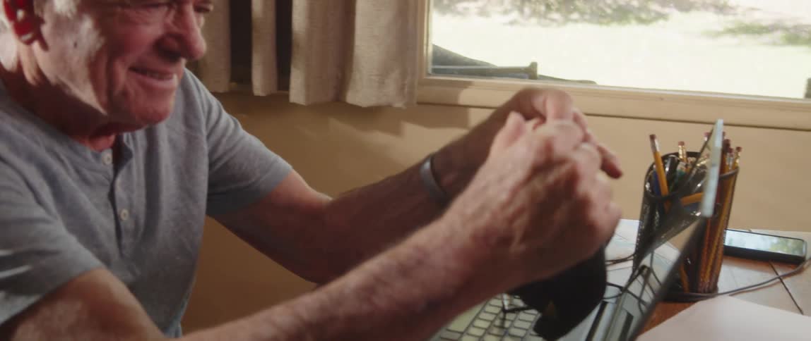 Elderly man sitting at home looks at his baseball cap