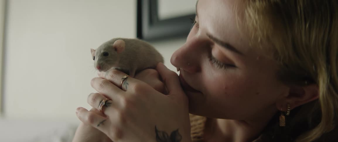 A young woman holds a pet rat in her hands