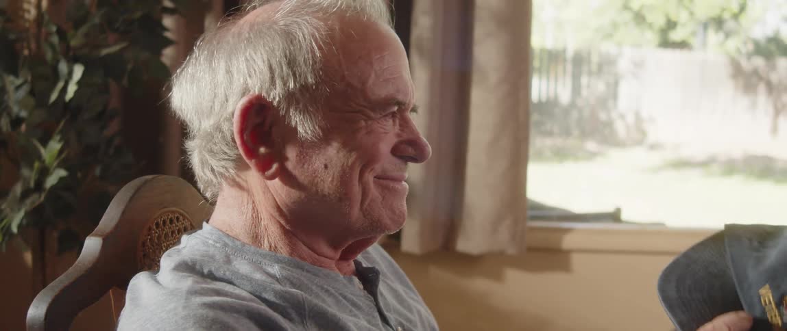 Elderly veteran considers his us army ball cap smiling as he reminisces