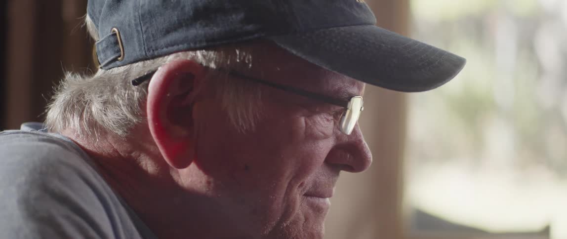 Elderly man puts on reading glasses and smiles while reading
