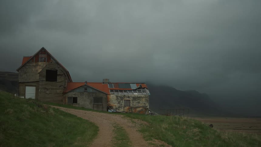 An old house on a hill near the mountains