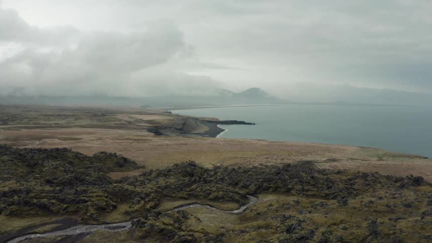 Aerial view of a coastline next to the mountains